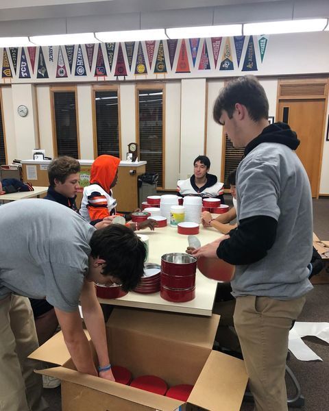 Here, students help Brother Sebastian label peanut brittle tins in preparation for the Christmas Season